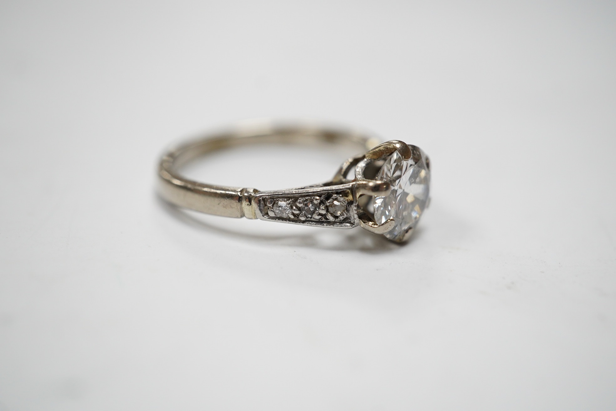 A white metal (stamped 18ct) and single stone diamond set ring, with six stone diamond set shoulders, the central stone weighing approximately 1.10ct, size M, gross weight 3.7 grams. Condition - poor to fair.